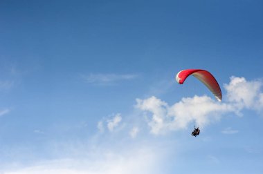 Yalnız yamaçparaşütü bulutlar arka planı mavi gökyüzünde uçan. Güneşli bir havada yamaç paraşütü.