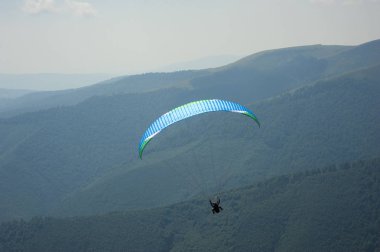 Yamaçparaşütü uçmak bir dağ Vadisi bir güneşli yaz gününde. Karpatlar yaz aylarında yapılan yamaç paraşütü.