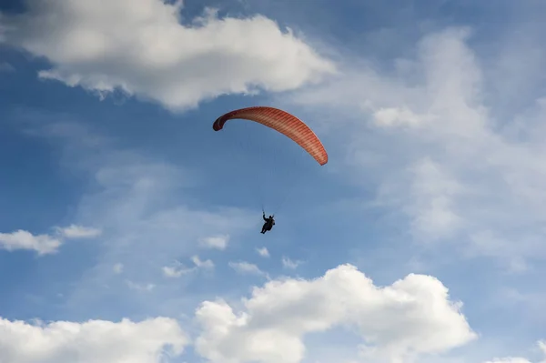 Parapente vermelho está voando no céu azul contra o fundo — Fotografia de Stock