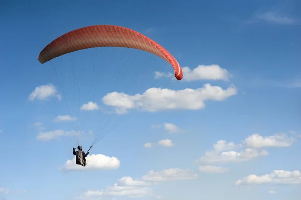 Red paraglider is flying in the blue sky against the background — Stock Photo, Image