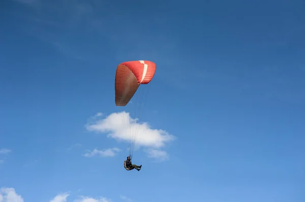 Parapente rouge vole dans le ciel bleu sur le fond — Photo