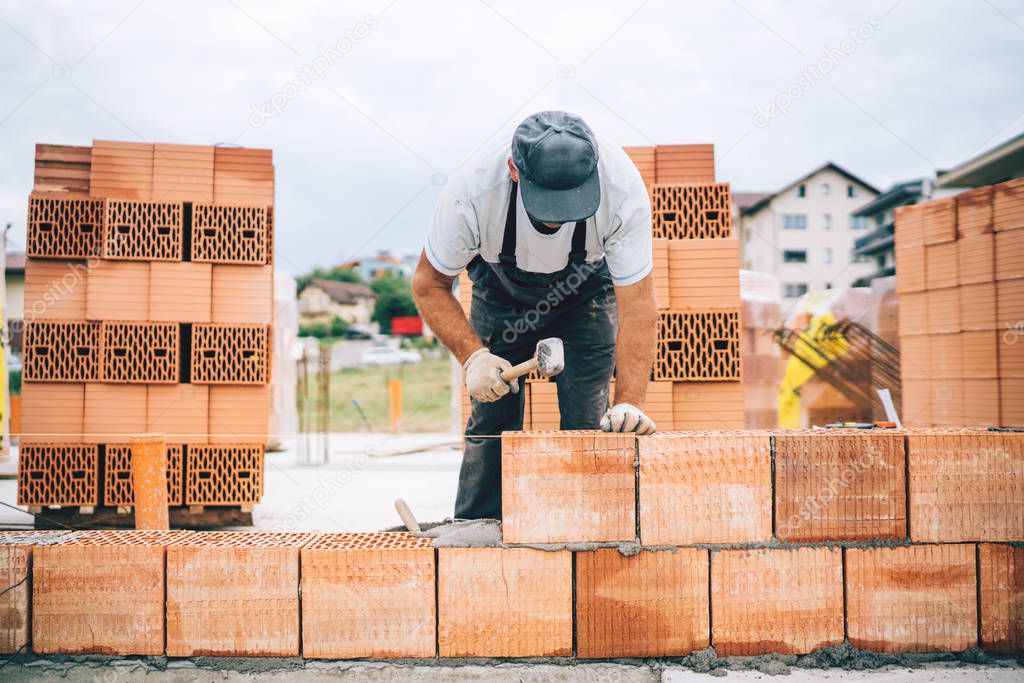 Close up details of industrial bricklayer installing bricks on construction sit