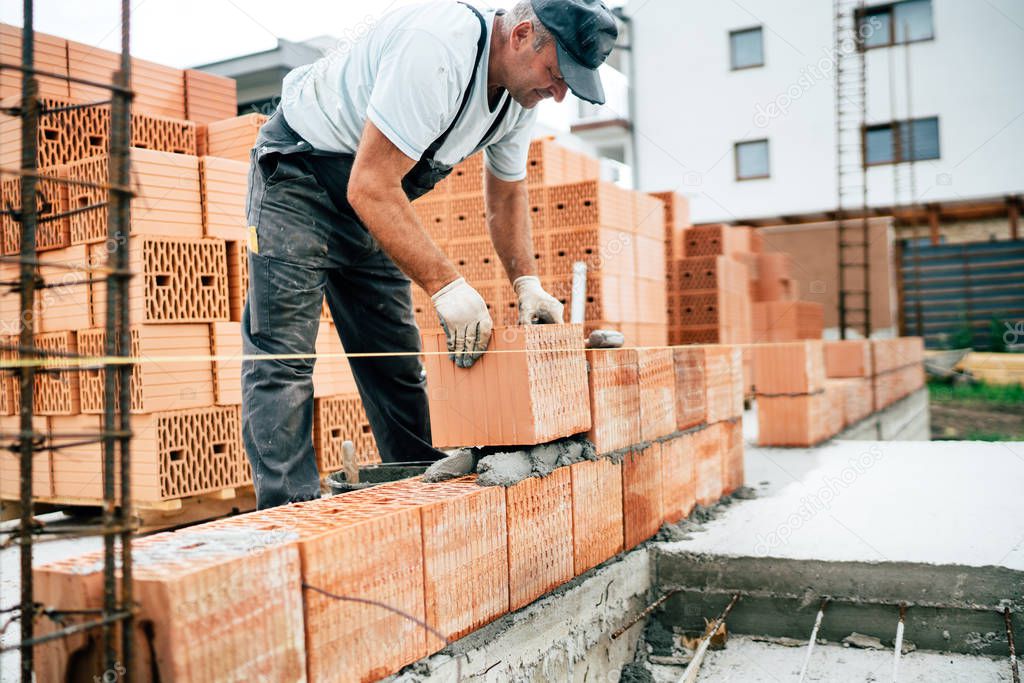 Professional industry worker using pan knife for building brick walls with cement and mortar