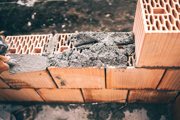 stock image Industrial worker using trowel and tools for building exterior walls with bricks, mortar and concrete