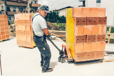 tuğla taşıma ve duvarlar binasında çalışan sanayi işçisi inşaat sitesinde