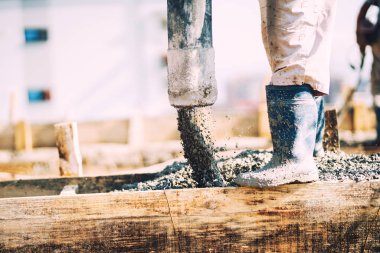 İnşaat sırasında dökülen betonun detayları. Endüstriyel detaylar, makineler ve insanlar