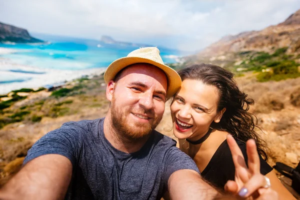 Selfie fotoğrafta Adası ve turkuaz su ile genç mutlu çift. Çiftlerin tatil içinde kendi kendine portre