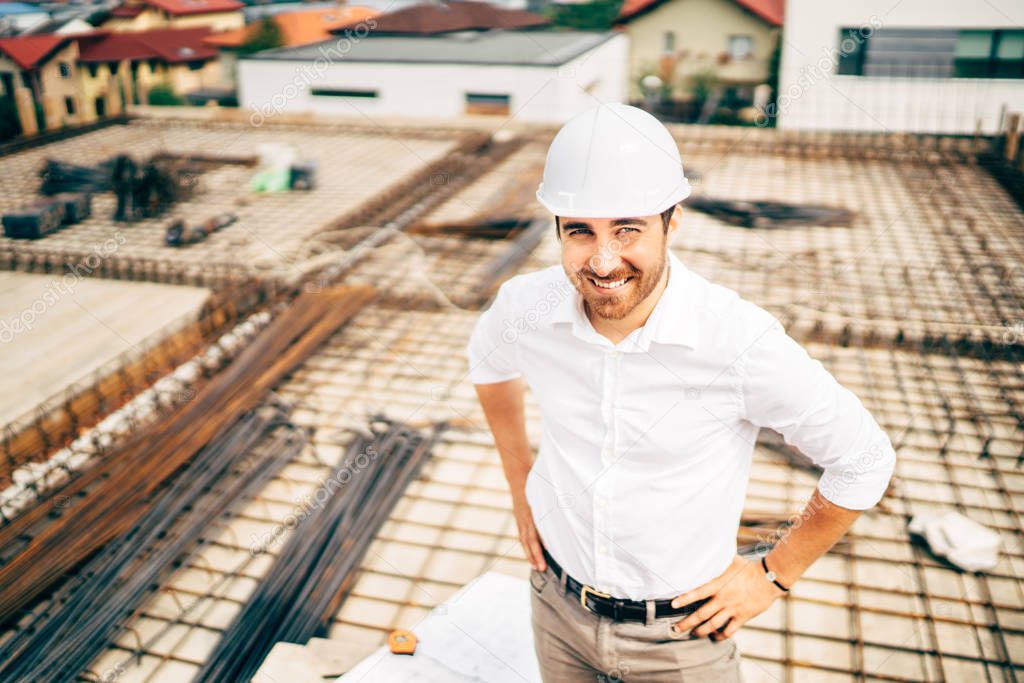 confident, smiling engineer and architect on construction site. Building construction site background
