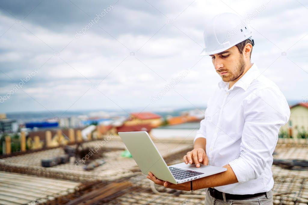 Supervisor engineer using laptop on construction site. Industry details