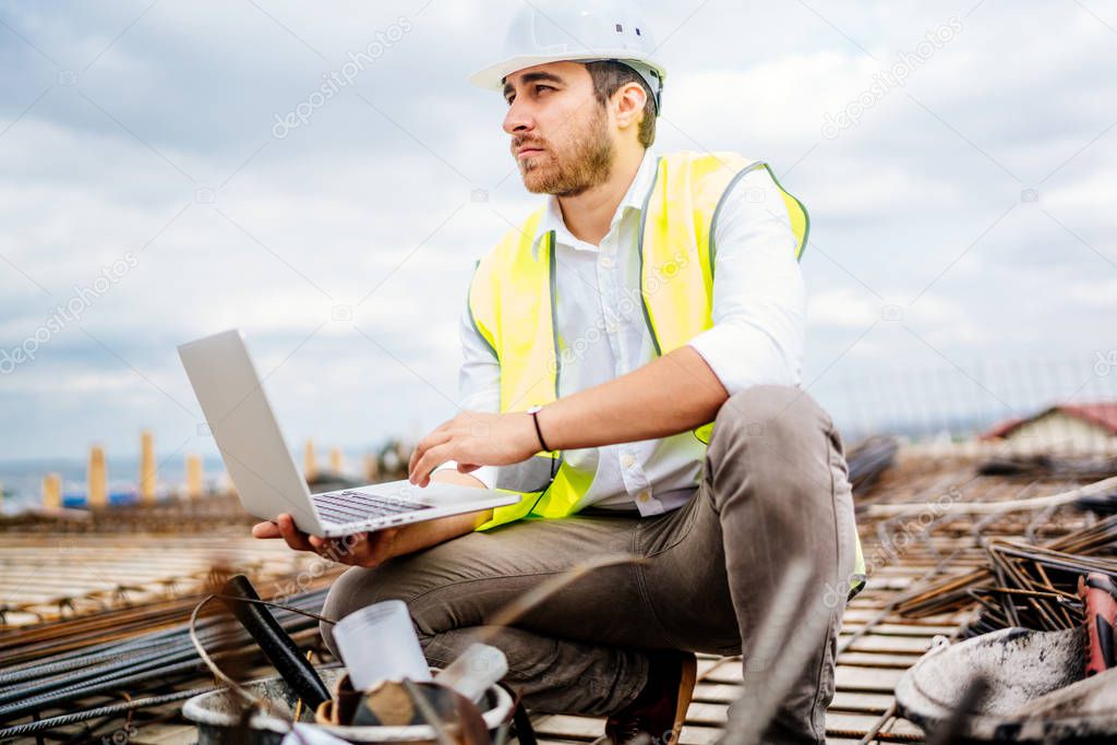 Dramatic view of civil construction engineer, working with laptop on construction site