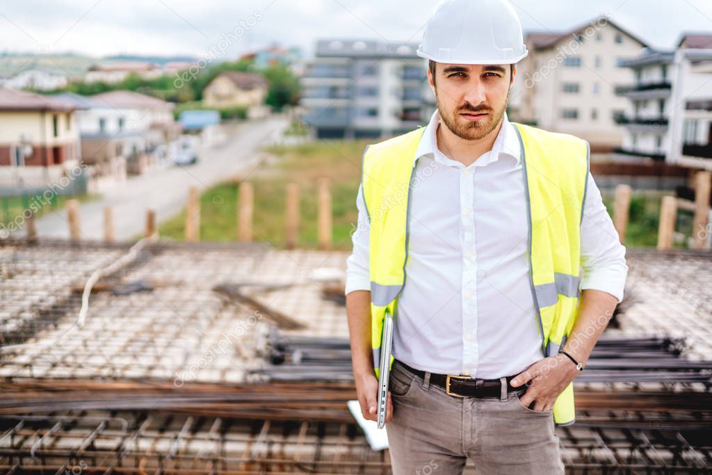 portrait of confident engineer working with laptop on construction site
