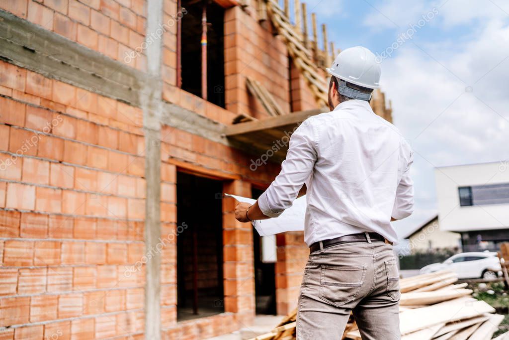 brick walls, infrastructure on construction site. construction engineer reading plans, working on building construction site.