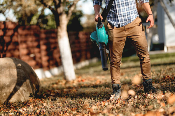 close up details of man using garden blower 