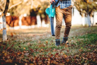 Ayrıntılar yaprak üfleme, bahçede çalışırken birden fazla aracı kullanan adam