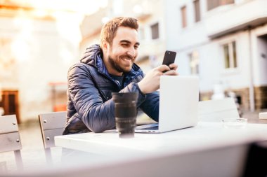 Açık office çalışma ve kentsel ortamda Smartphone cep telefonu ile mesaj göndermek gülümseyen adam