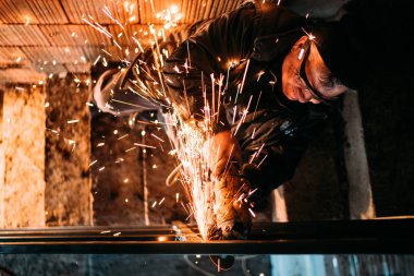 kesme demir üzerinde çalışan İnşaat Sanayi orta yaşlı erkeğin çubukları, güvenlik ekipmanları kullanarak açı değirmeni ile çelik çubukları