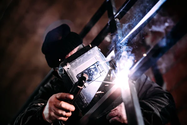 Retrato de soldador profissional com engrenagem de proteção trabalhando em grades de metal — Fotografia de Stock