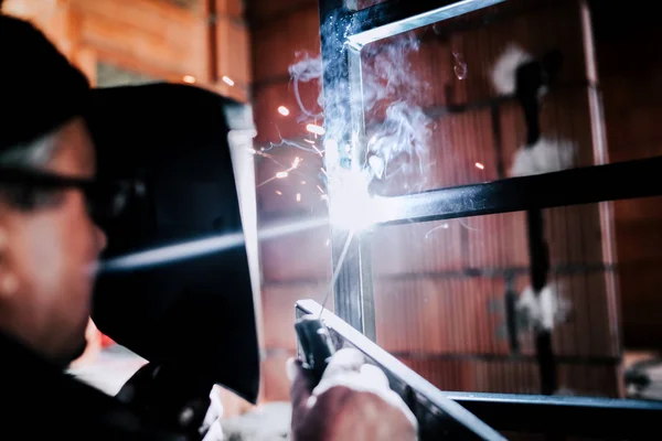 Portrait of caucasian male worker welding metal structure — Stock Photo, Image