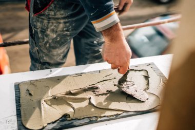 seramik karolar. işçinin elmermer, taş üzerine yapıştırıcı ekleyerek