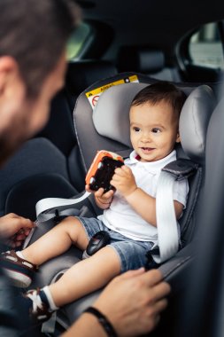 portrait of smiling baby and father in car child seat clipart