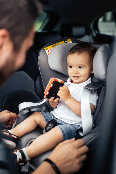 portrait of smiling baby and father in car child seat