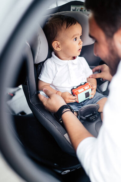 Family transportation, lifestyle concept - Father putting baby in child seat, fastening seatbelt