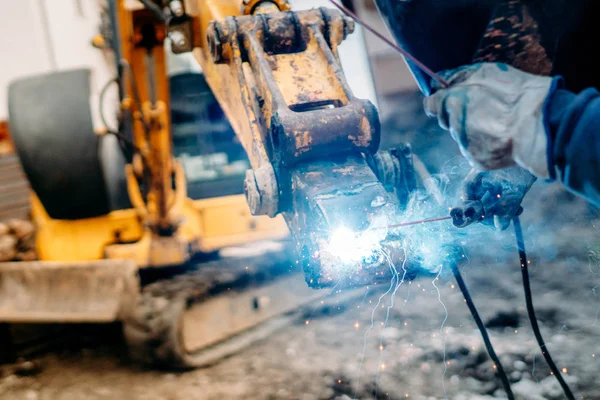 Industrial machinery being rapaired on construction site. mechanic welder working on excavator — Stock Photo, Image