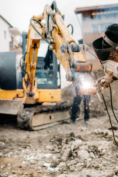 Närbild Detaljer av professionella svetsare som arbetar på trasiga grävmaskin, reparation och arbete — Stockfoto