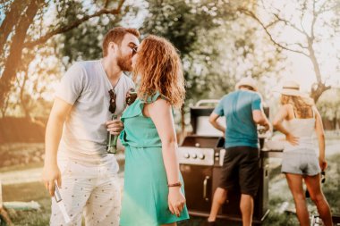 Barbekü partisinde öpüşen mükemmel beyaz çiftin portresi, iyi vakit geçiren arkadaşlar