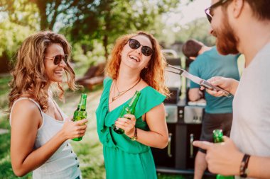 Bir grup arkadaş açık bahçe barbekü sahip. Kızlar iyi vakit geçiriyor, gülüyor ve gülümsüyor