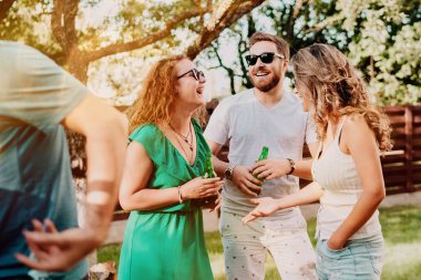 Arkadaşlar ormanda bir barbekü partisinde içki ve gülümseyerek öğle yemeği yiyor. Pazar chill kavramı