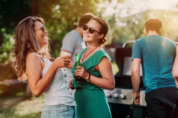 Millennials meninas rindo e sorrindo na festa de churrasco, tomando bebidas e conversando com os amigos. Conceito de estilo de vida — Fotografia de Stock