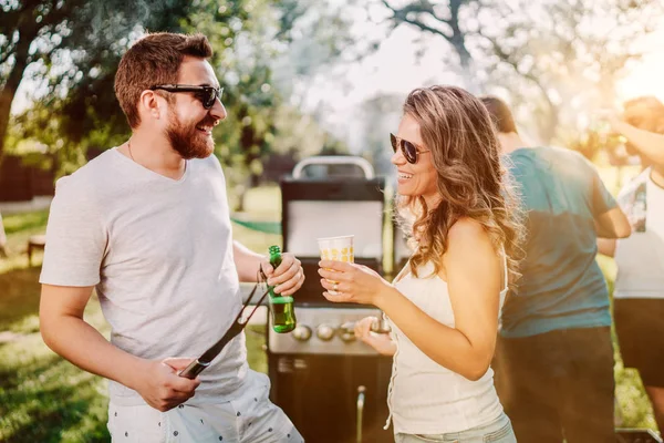 Amigos que fazem uma festa de churrasco com bebidas, comida e cozinha ao ar livre na natureza — Fotografia de Stock