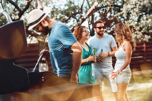 Grupo de amigos se divertindo em uma festa de churrasco e churrasqueira. Sorrindo, bebendo e rindo — Fotografia de Stock