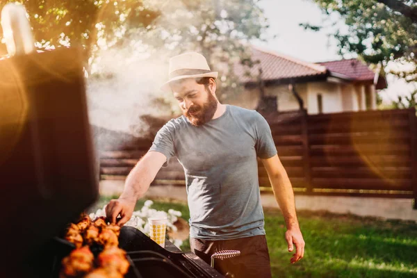 Bonito sorriso, feliz macho preparando churrasqueira com carne e legumes para amigo — Fotografia de Stock