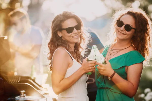 Mädchen tanzen auf Grillparty, Freunde trinken Bier und Jungs kochen im Hintergrund — Stockfoto