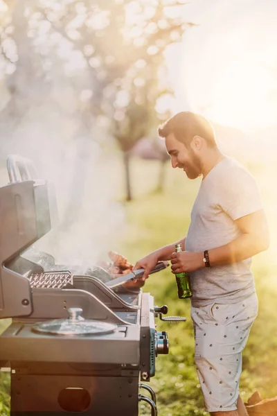 Porträt eines lachenden, gutaussehenden Typen, der sich bei Grillparty, Kochen und Biertrinken amüsiert — Stockfoto