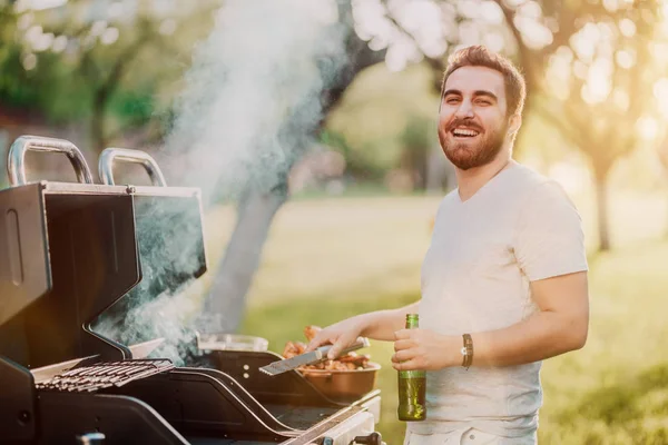 Porträt eines lachenden, gutaussehenden Typen, der sich bei Grillparty, Kochen und Biertrinken amüsiert — Stockfoto