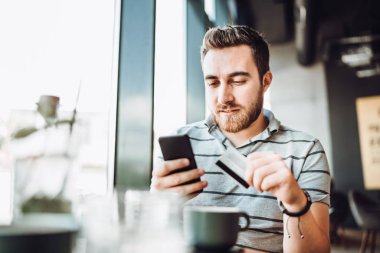 Adam online alışveriş için akıllı telefon ve kredi kartı kullanıyor.