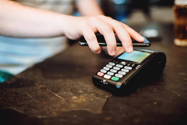 Homem usando smartphone com tecnologia nfc e pagando no restaurante — Fotografia de Stock