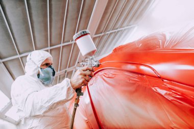 sprey tabancası kullanarak ve kırmızı bir araba boyama otomotiv endüstrisi mekanik mühendis işçi