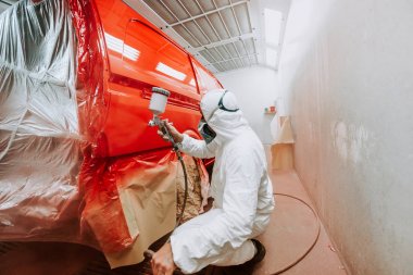 işçi özel bir garajda kırmızı bir araba boyama, beyaz bir costum giyen