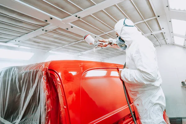 Auto painter spraying red paint on van, car in auto workshop — Stock Photo, Image