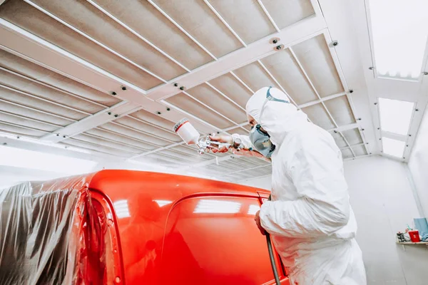 Auto mechanik malarz malarstwo czerwony samochód, van w specjalnym stoisku — Zdjęcie stockowe