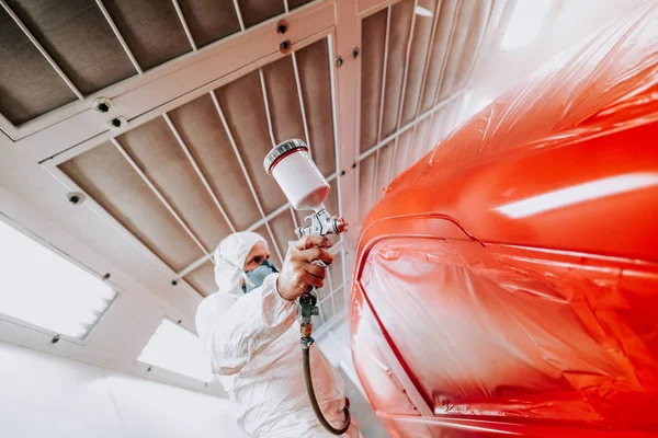 Details van de automobielindustrie-monteur ingenieur met behulp van spuitpistool en het schilderen van een rode auto — Stockfoto