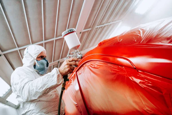 Ingeniero mecánico de la industria automotriz con pistola de pulverización y pintura de un coche rojo —  Fotos de Stock