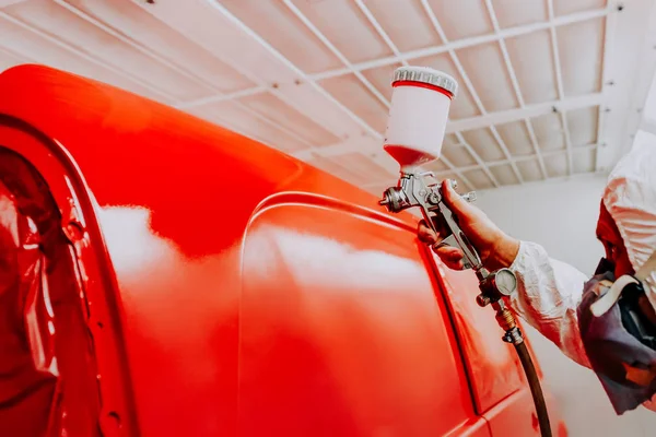 Auto painter spraying red paint on car in auto worksho — Stock Photo, Image