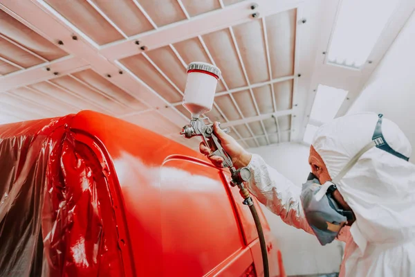 Close up of automobile mechanic worker painting a red car with spray gun — Stock Photo, Image