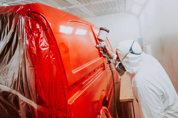 Automotive industry - engineer painting and working on a red bodywork of a car and wearing protective gea — Stock Photo, Image