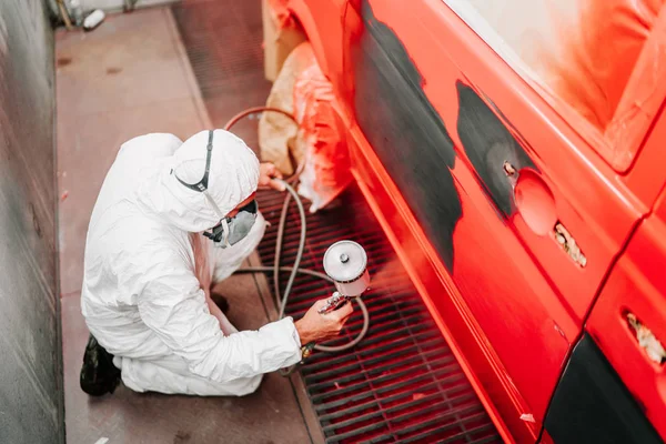 Auto mechanik malarz malarstwo czerwony samochód, van w specjalnym stoisku. Szczegóły dotyczące przemysłu motoryzacyjnego — Zdjęcie stockowe